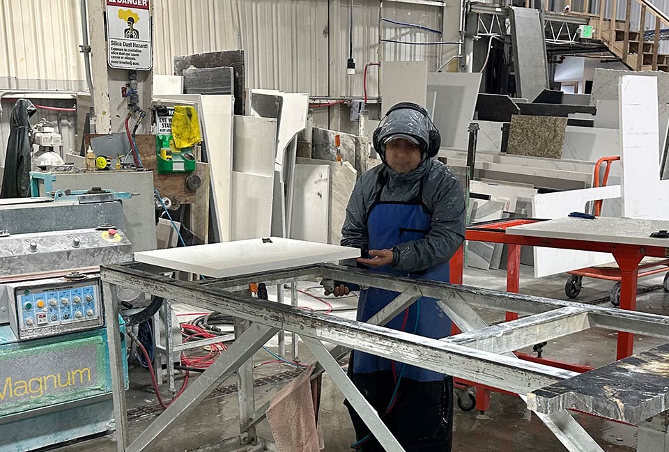 L&I photo shows A+ Marble & Granite worker polishing a stone slab without wearing respiratory protection.