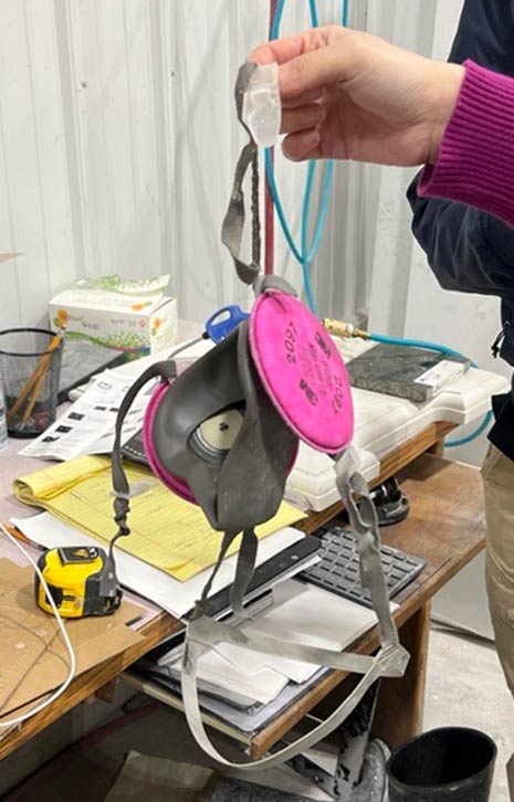 L&I photo shows a half face air purifying respirator with frayed straps and stone dust contamination.